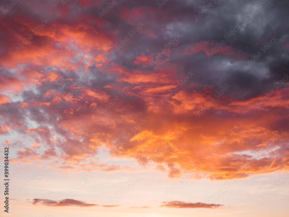 Gorgeous sunset with clouds of different shapes. Evening sky with orange, red and violet fluffy clouds. Colorful cloudscape.