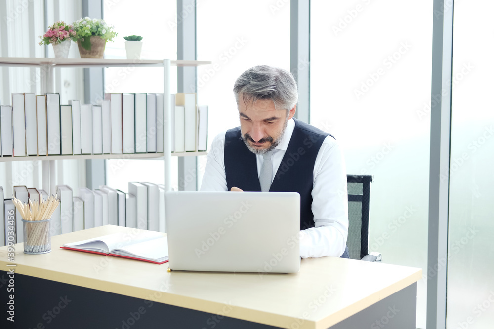 Smiling Smart Caucasian senior manager and businessman in black suit is working with laptop at workspace in modern office. Smiling Smart Caucasian senior manager and businessman in black suit is working with laptop at workspace in modern office.