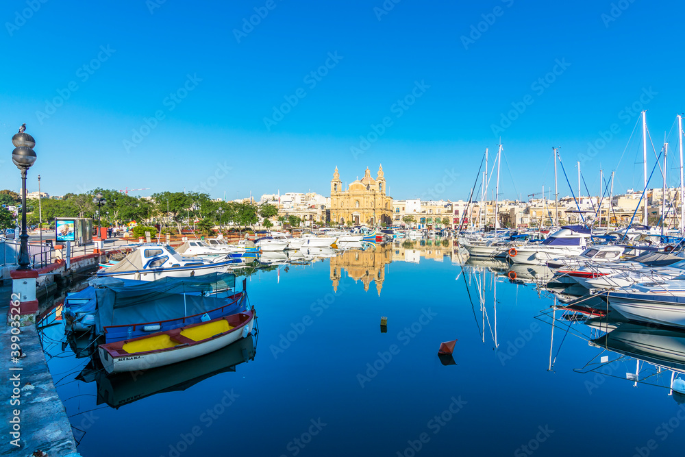 The Msida (Imsida) harbor view with beautiful mirror reflection of boats and Parish Churc  in west of Valletta, Malta.