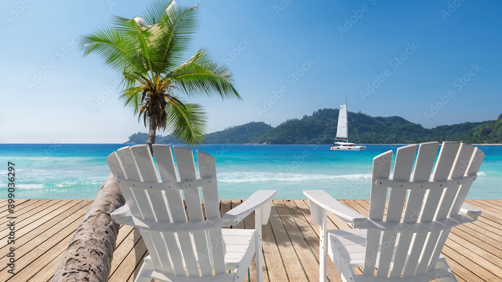 Sunny Caribbean beach with white chairs on wooden floor, palm trees and a sailing boat in the turquoise sea on Paradise island.
