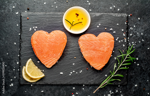 Two raw salmon fillets with heart shaped spices on a stone background