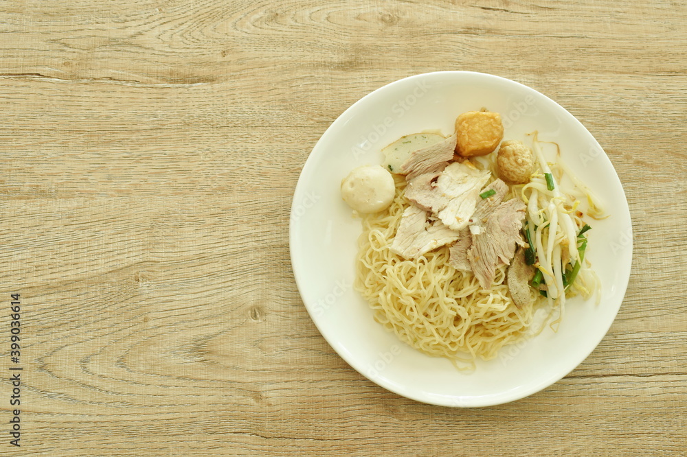 dry Chinese egg yellow noodles topping slice boiled pork and ball on plate