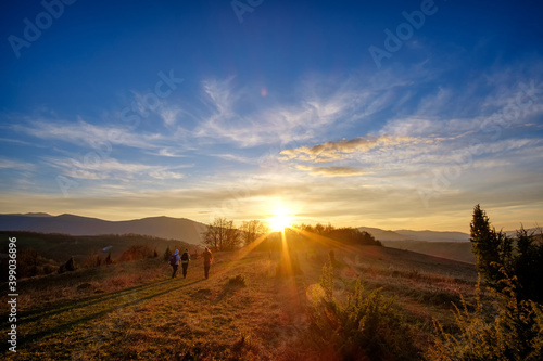 Beautiful sunset in the autumn in the mountains, rich colors. Three tourists follow the sun along the road
