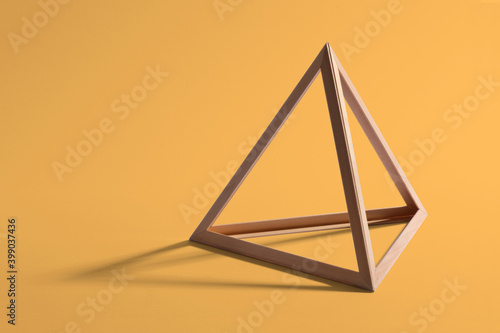 Wooden triangular frame on yellow background photo