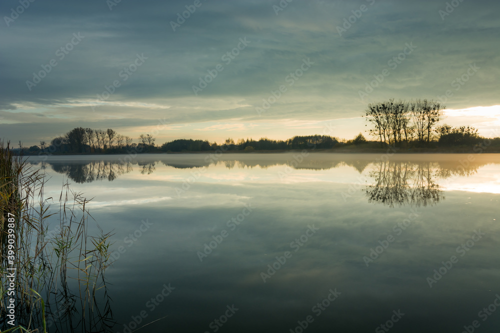 Fog on a quiet lake and evening clouds