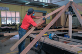 The carpenter  using  cordless drill  for installing   roof rafters on a new gazebo construction project