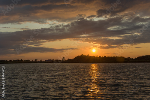 Quiet lake, evening clouds and sun over the horizon © darekb22