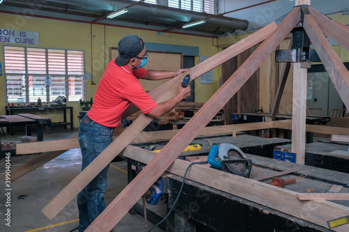 The carpenter using cordless drill for installing roof rafters on a new gazebo construction project