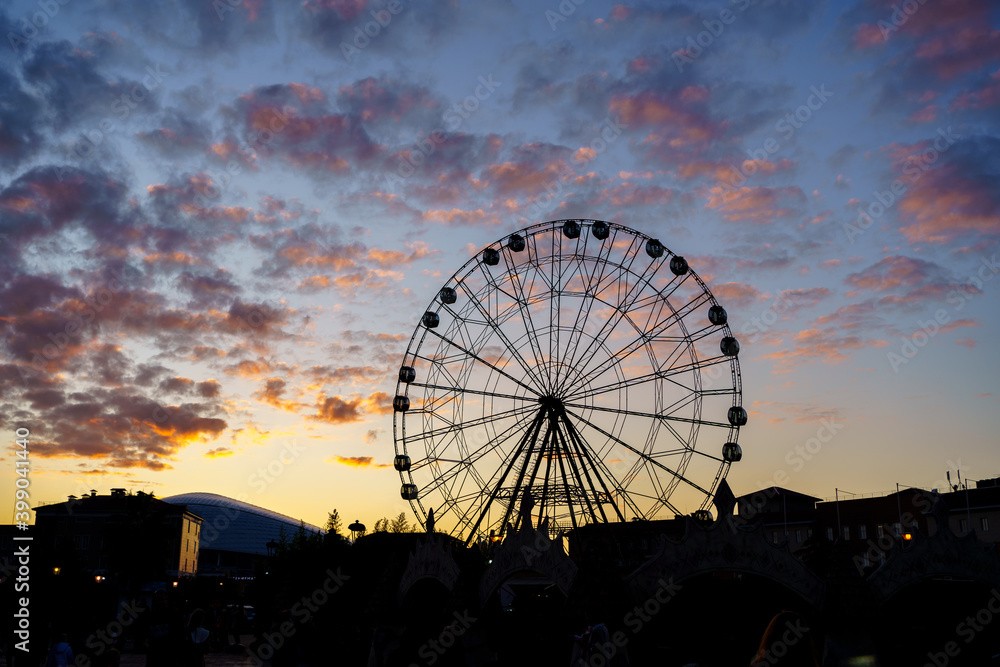 Ferris wheel against a sunset sky with clouds. entertainment for tourists. 