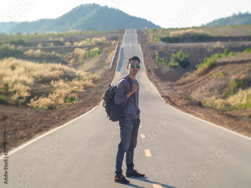 A man with a backpack standing in the middle of the road