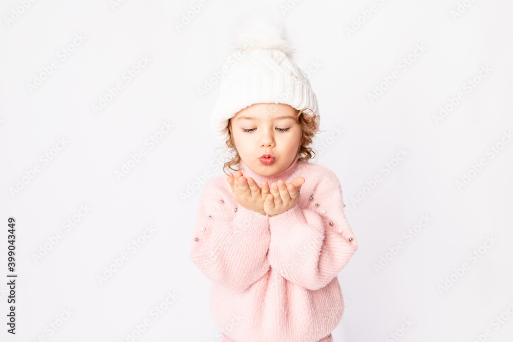 cute baby girl in pink winter clothes on a white background blows off her hands, space for text cute baby girl in pink winter clothes on a white background blows off her hands, space for text