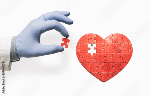 Heart-shaped puzzle and doctor's hand with the missing piece of puzzle. Heart treatment concept. photo