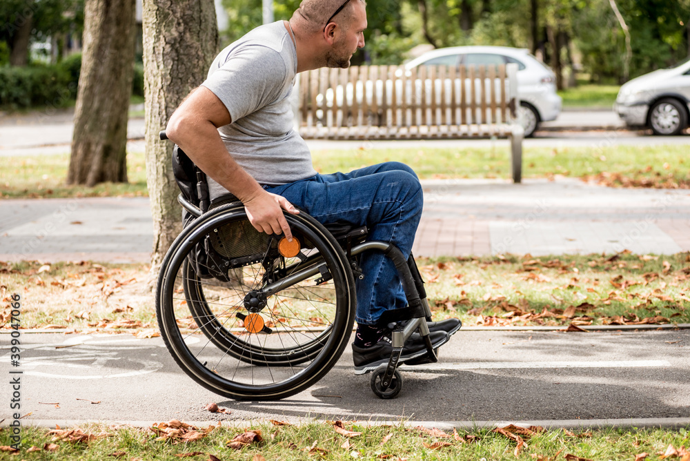 Handicapped man in wheelchair walk at the park alley Handicapped man in wheelchair walk at the park alley