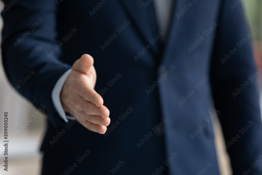 Close up businessman wearing suit extending hand for handshake to business partner or customer at meeting, hr manager greeting candidate at job interview, first impression or acquaintance