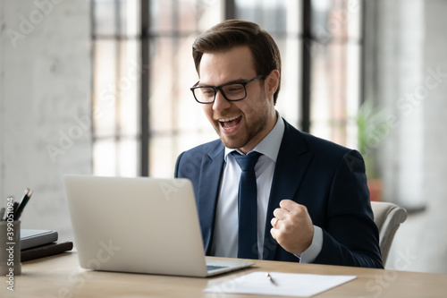 Photos Close up overjoyed businessman wearing glasses excited by good news reading in e