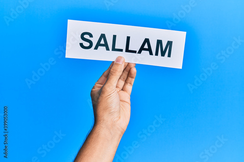 Hand of hispanic man holding sallam word paper over isolated blue background. photo