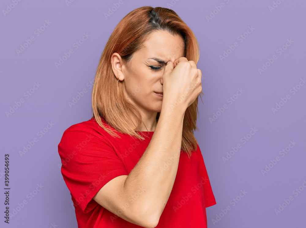 Hispanic young woman wearing casual red t shirt tired rubbing nose and eyes feeling fatigue and headache. stress and frustration concept. Hispanic young woman wearing casual red t shirt tired rubbing nose and eyes feeling fatigue and headache. stress and frustration concept.