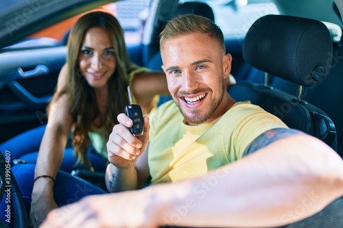 Young couple smiling happy holding key at the car.