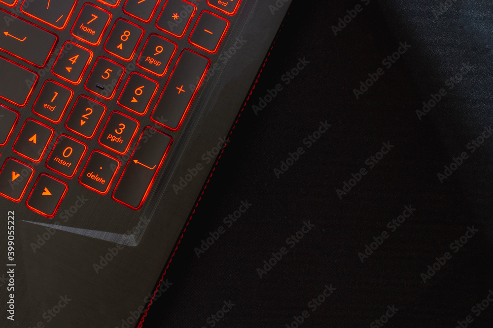 Obraz premium Laptop keyboard with red backlight on a black mouse pad. Background. Copy space.