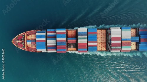 Aerial top view of smart cargo ship carrying container and running very fast for export cargo from container yard port to custom ,Contrail line in the ocean by large ship very fast. 