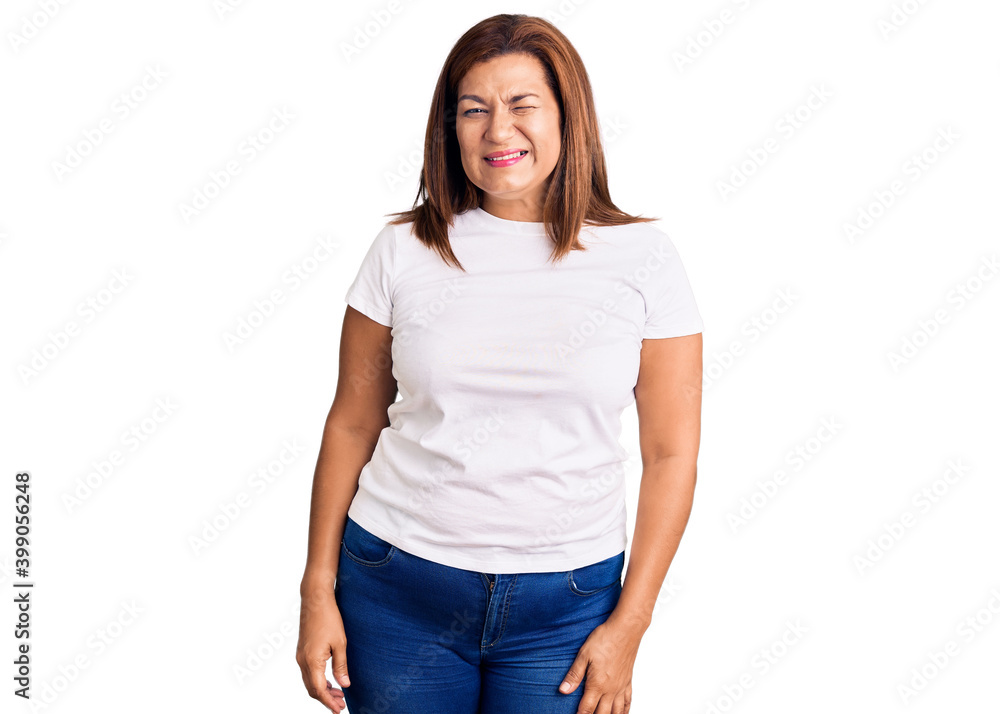 Middle age latin woman wearing casual white tshirt winking looking at the camera with sexy expression, cheerful and happy face. Middle age latin woman wearing casual white tshirt winking looking at the camera with sexy expression, cheerful and happy face.