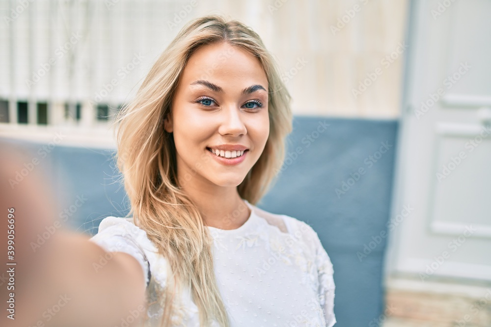 Young caucasian girl smiling happy making selfie by the camera at street of city.