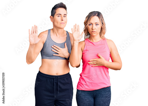 Couple of women wearing sportswear swearing with hand on chest and open palm, making a loyalty promise oath © Krakenimages.com