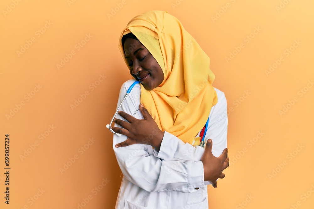 Beautiful african young woman wearing doctor uniform and hijab hugging oneself happy and positive, smiling confident. self love and self care Beautiful african young woman wearing doctor uniform and hijab hugging oneself happy and positive, smiling confident. self love and self care