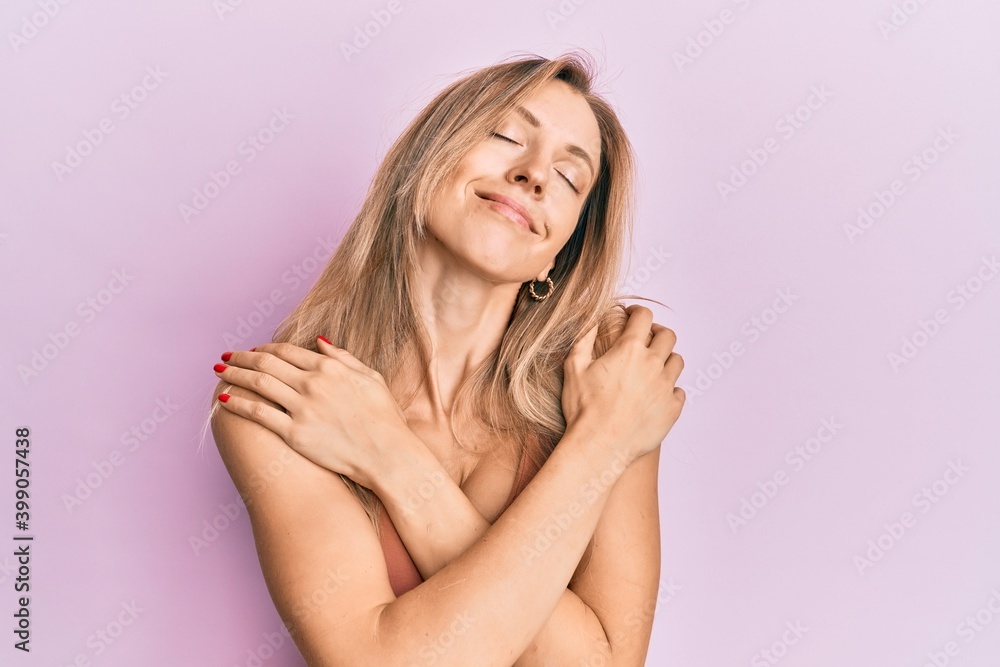 Beautiful caucasian woman wearing casual clothes hugging oneself happy and positive, smiling confident. self love and self care Beautiful caucasian woman wearing casual clothes hugging oneself happy and positive, smiling confident. self love and self care