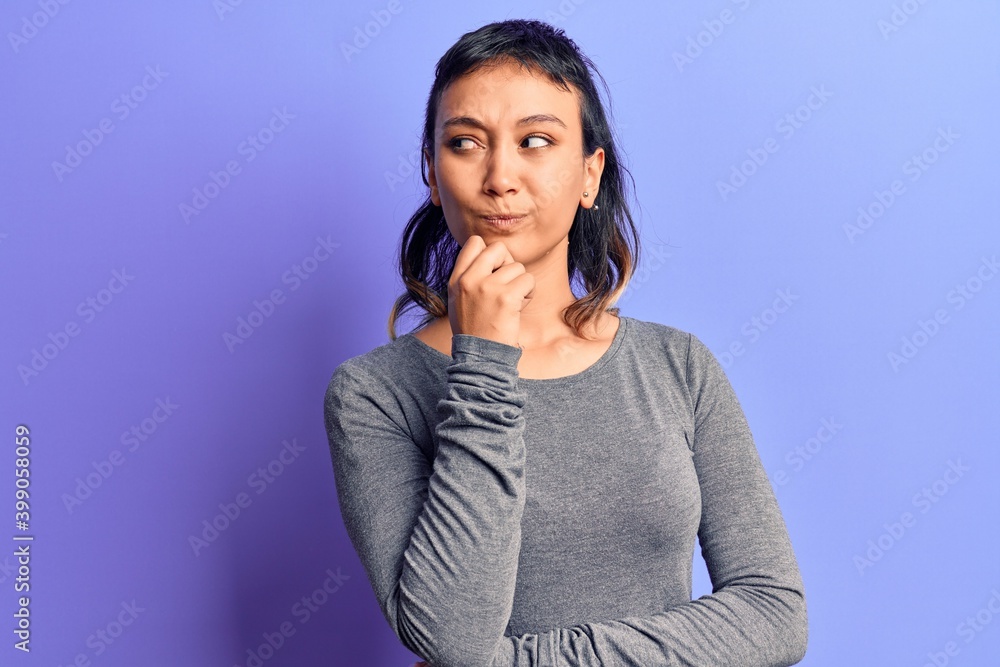Young woman wearing casual clothes thinking concentrated about doubt with finger on chin and looking up wondering Young woman wearing casual clothes thinking concentrated about doubt with finger on chin and looking up wondering