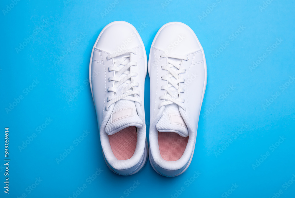 Pair of stylish sport shoes on blue background. Top view of white sneakers on color background Pair of stylish sport shoes on blue background. Top view of white sneakers on color background