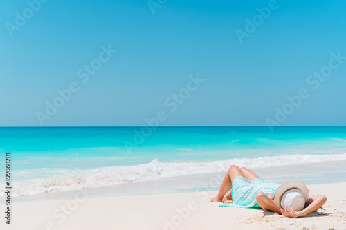 Fototapeta Naklejka Na Ścianę i Meble -  Woman laying on the beach enjoying summer holidays looking at the sea