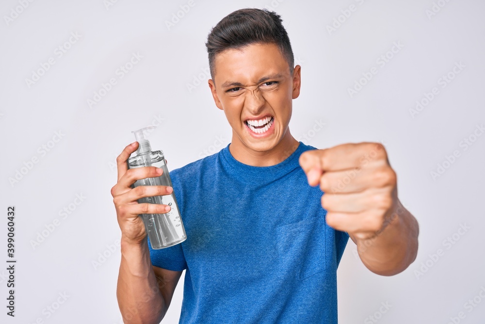 Young hispanic boy using hand sanitizer gel annoyed and frustrated shouting with anger, yelling crazy with anger and hand raised Young hispanic boy using hand sanitizer gel annoyed and frustrated shouting with anger, yelling crazy with anger and hand raised