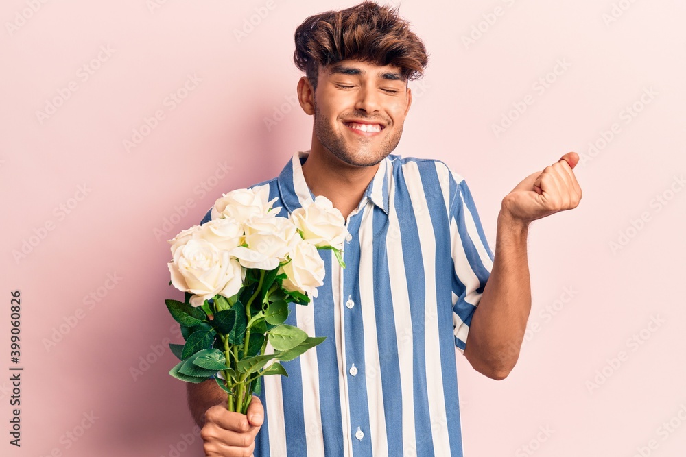 Young hispanic man holding flowers screaming proud, celebrating victory and success very excited with raised arm Young hispanic man holding flowers screaming proud, celebrating victory and success very excited with raised arm