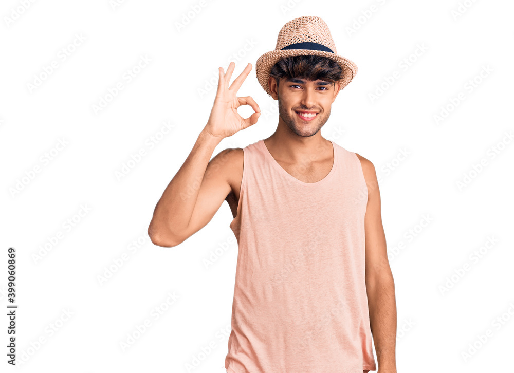 Young hispanic man wearing summer hat smiling positive doing ok sign with hand and fingers. successful expression. Young hispanic man wearing summer hat smiling positive doing ok sign with hand and fingers. successful expression.