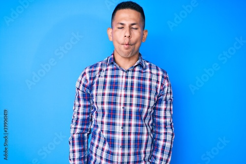 Young handsome latin man wearing casual clothes making fish face with lips, crazy and comical gesture. funny expression.
