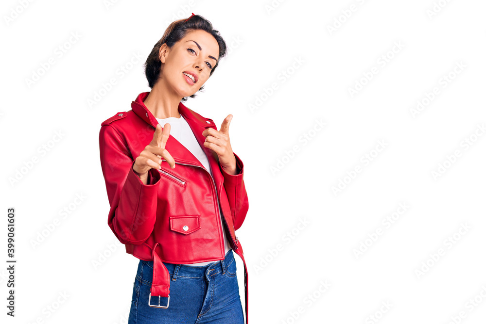 Young beautiful woman wearing red leather jacket pointing fingers to camera with happy and funny face. good energy and vibes. Young beautiful woman wearing red leather jacket pointing fingers to camera with happy and funny face. good energy and vibes.