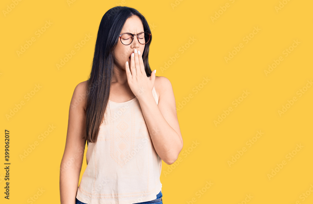 Young beautiful caucasian woman wearing casual clothes and glasses bored yawning tired covering mouth with hand. restless and sleepiness. Young beautiful caucasian woman wearing casual clothes and glasses bored yawning tired covering mouth with hand. restless and sleepiness.