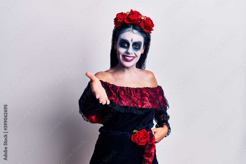 Young woman wearing mexican day of the dead makeup smiling cheerful offering palm hand giving assistance and acceptance.