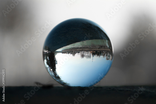 A riverside highway view through a lens ball. Glass ball with inverted view.
