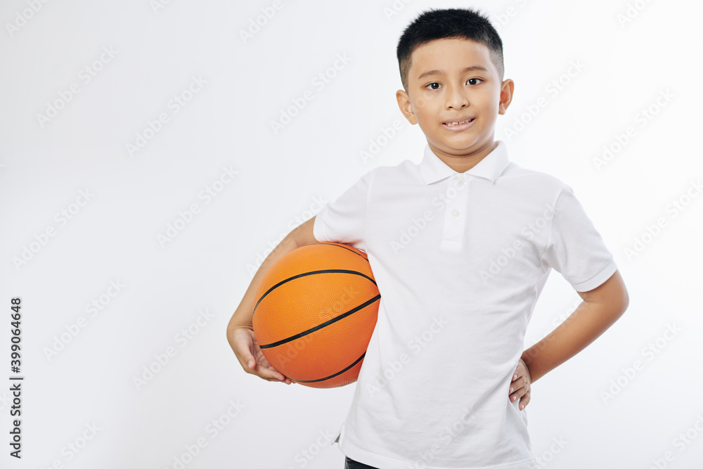 Portrait of cheerful Asian preteen boy posing with basketball ball and looking at camera Portrait of cheerful Asian preteen boy posing with basketball ball and looking at camera