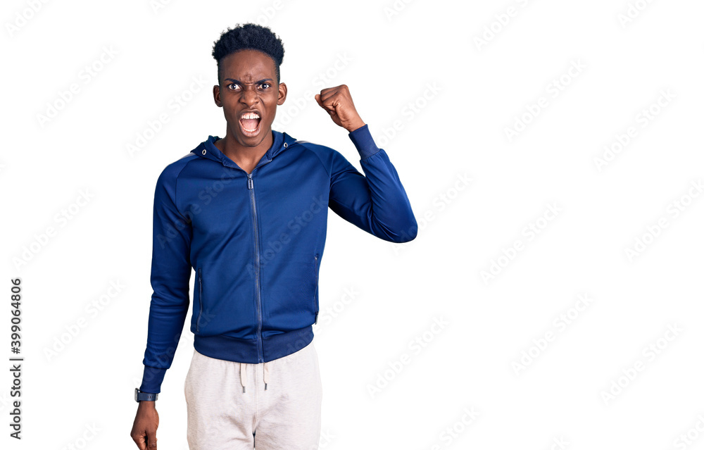 Naklejka premium Young african american man wearing sportswear angry and mad raising fist frustrated and furious while shouting with anger. rage and aggressive concept.