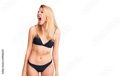 Young beautiful blonde woman wearing bikini angry and mad screaming frustrated and furious, shouting with anger. rage and aggressive concept.