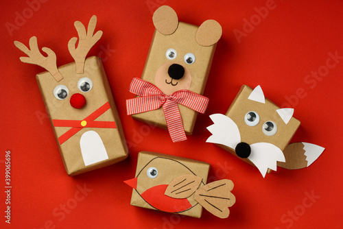 Childrens Christmas gifts in craft paper bear, deer, bird and fox on a red background. Top view. New year christmas  holiday concept photo