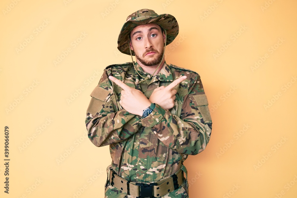 Young caucasian man wearing camouflage army uniform pointing to both sides with fingers, different direction disagree Young caucasian man wearing camouflage army uniform pointing to both sides with fingers, different direction disagree