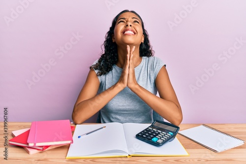 Young african american girl accountant working at the office begging and praying with hands together with hope expression on face very emotional and worried. begging.