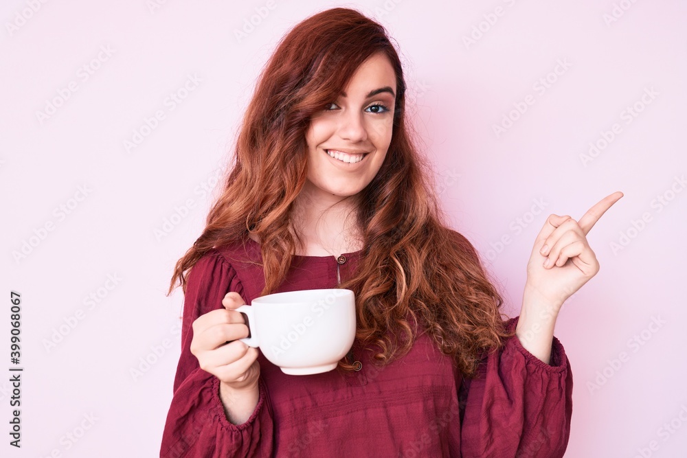 Young beautiful woman holding coffee smiling happy pointing with hand and finger to the side Young beautiful woman holding coffee smiling happy pointing with hand and finger to the side