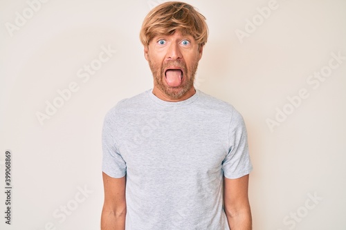 Young blond man wearing casual clothes sticking tongue out happy with funny expression. emotion concept. © Krakenimages.com