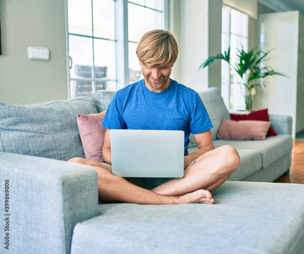 Middle age handsome caucasian man relaxing at home working with computer laptop on the sofa Middle age handsome caucasian man relaxing at home working with computer laptop on the sofa