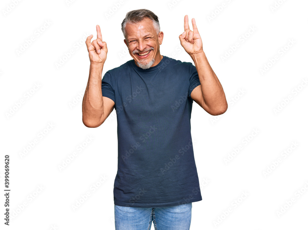 Middle age grey-haired man wearing casual clothes shouting with crazy expression doing rock symbol with hands up. music star. heavy concept. Middle age grey-haired man wearing casual clothes shouting with crazy expression doing rock symbol with hands up. music star. heavy concept.